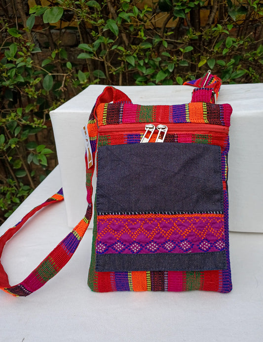 A cross body bag made with denim and handwoven material. Embellished with hand embroidery. Made with multiple pockets and a waterproof inner lining.